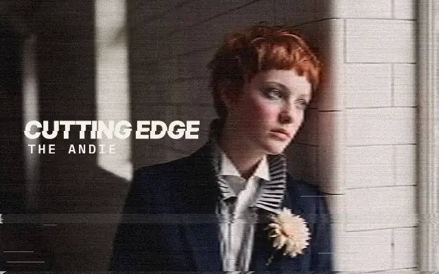 AI-generated image: The Andie, The Cutting Edge: a woman with a short copper textured pixie and a short blunt fringe, in a dark jacket with a pleated collar, leaning on white tiles
